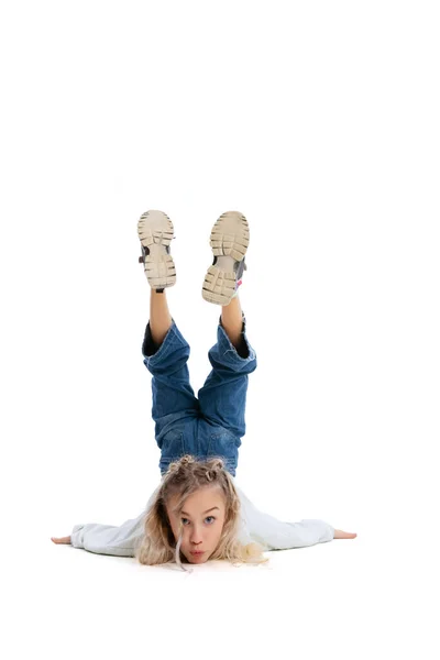 Leuk grappig klein meisje, flexibel kind in casual kleding hebben plezier geïsoleerd op witte studio achtergrond. Emoties — Stockfoto