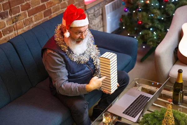 Vista superior del viejo barbudo con sombrero de Navidad sentado en casa y celebra el Año Nuevo con amigos y familiares por medio de videollamada. — Foto de Stock