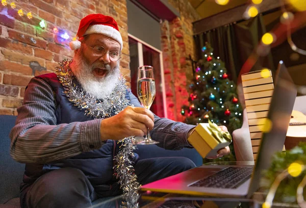 Hombre barbudo viejo emocional sentado en casa y celebra el Año Nuevo con amigos y familiares por medio de videollamada. — Foto de Stock