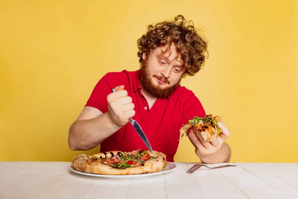 노란색 스튜디오 배경에 고립된 맛있는 이탈리아 피자를 먹을 준비를 하고 있는 붉은 수염 남자의 모습. — 스톡 사진