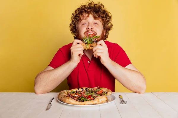 붉은 수염의 남자가 노란색 스튜디오 배경에 따로 놓아둔 맛있는 이탈리아 피자를 맛보는 모습. — 스톡 사진