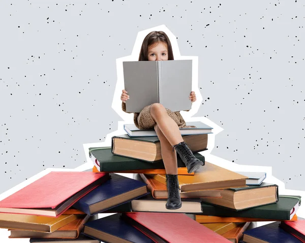 Diseño creativo niña curiosa, niño sentado en la pila de libros y la lectura aislado sobre fondo gris —  Fotos de Stock