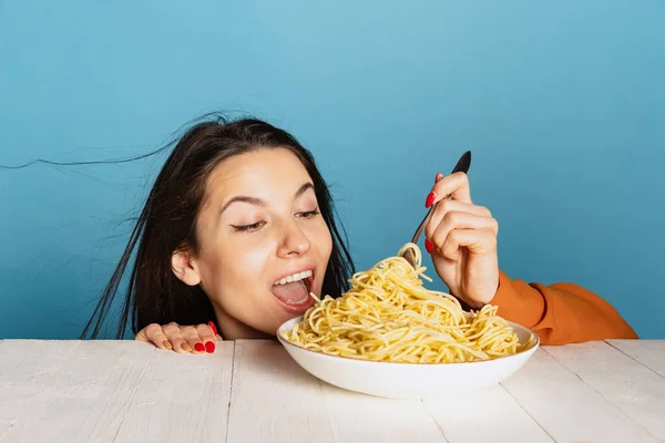 Excited young girl preparing to eat large portion of noodles isolated on blue studio background. World pasta day — Stock Photo, Image