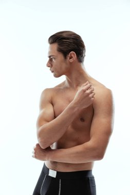 Beyaz arka planda tek başına duran siyah boxer külotlu genç, üstsüz, yakışıklı bir adamın yarım boy portresi..