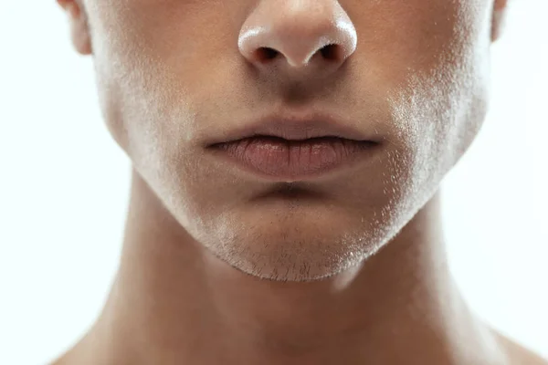 Χείλη. Κοντινό πρόσωπο ενός νεαρού άνδρα απομονωμένου σε λευκό φόντο στούντιο. Έννοια της μόδας και της ομορφιάς, της αυτο-φροντίδας, του σώματος και της φροντίδας του δέρματος. — Φωτογραφία Αρχείου