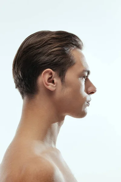 Vista del perfil de un joven guapo aislado sobre fondo blanco del estudio. Concepto de salud y belleza para hombre —  Fotos de Stock