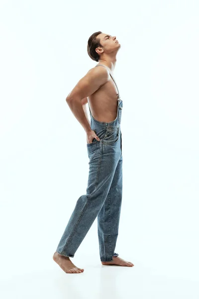 Портрет молодого красивого спортсмена без сорочки в джинсах позує ізольовано на білому фоні студії . — стокове фото