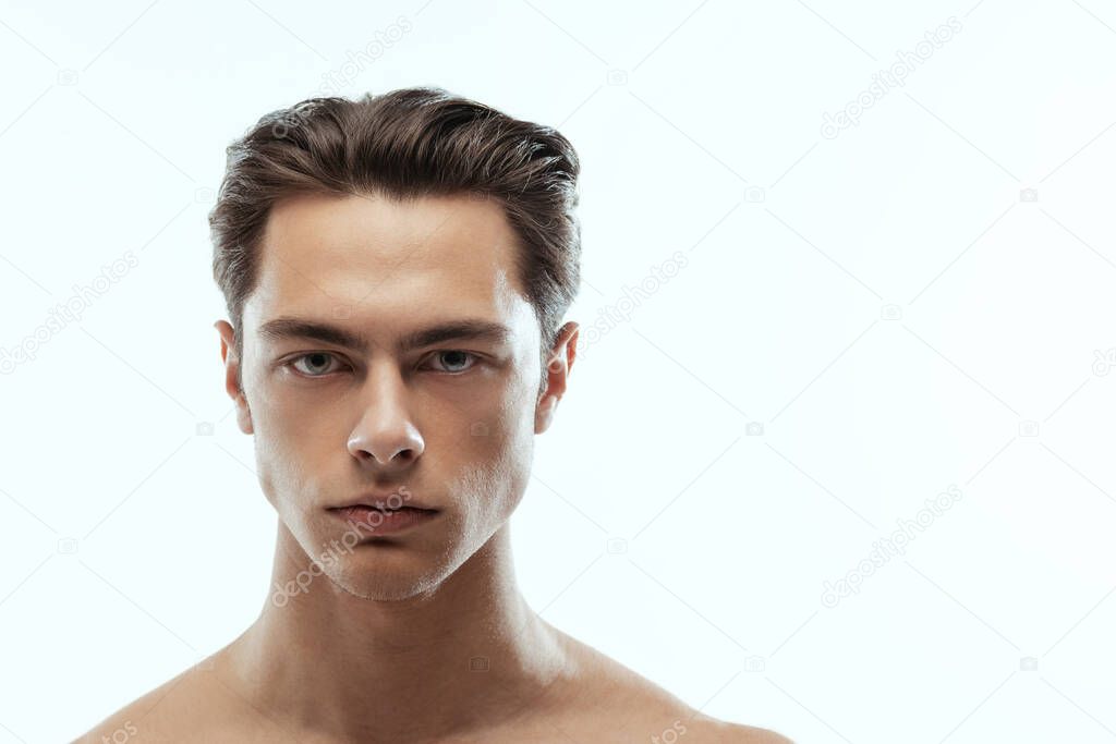 Close-up portrait of young handsome man isolated on white studio background. Concept of mens health and beauty