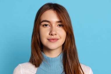 Gülümseyen güzel kadın portresi mavi stüdyo arka planında izole edilmiş. İnsani duygular, yüz ifadesi kavramı