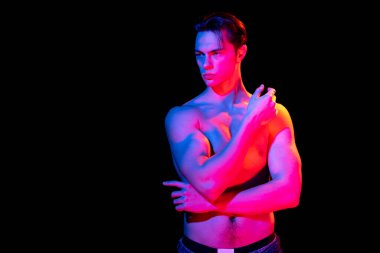 Yakışıklı genç adam portresi karanlık stüdyo arka planında pembe neon ile izole edilmiş, insan duyguları kavramı, yüz ifadesi