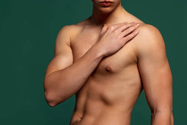 Обрезанный портрет молодого красивого спортивного мужчины без рубашки, изолированного на зеленом фоне. Мышечное мужское тело — стоковое фото