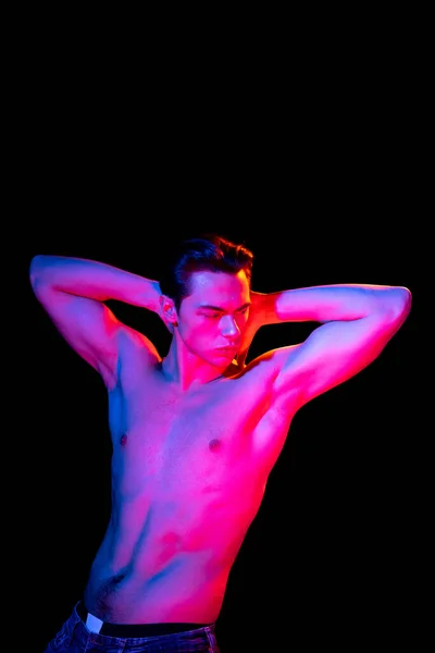 Genç adam portresi, karanlık stüdyo arka planında pembe neonlarla izole edilmiş, insan duyguları kavramı, yüz ifadesi. — Stok fotoğraf