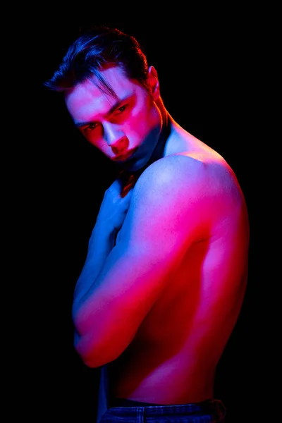 Guapo joven hombre retrato aislado en oscuro estudio fondo en neón rosa, concepto de emociones humanas, expresión facial —  Fotos de Stock