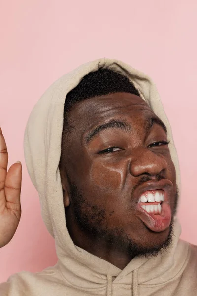 Jeune bel homme, étudiant appuyé sur un verre transparent isolé sur fond de studio rose. Gros plan — Photo