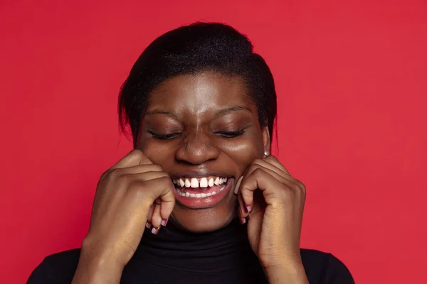 Portrait of young dark skinned girl laughing isolated on dark red studio background. Concept of emotions, facial expressions — Stockfoto