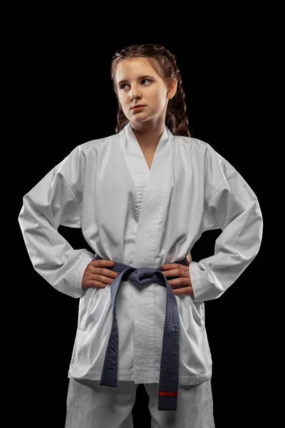 Una joven, adolescente, atleta taekwondo posando aislada sobre un fondo oscuro. Concepto de deporte, educación, habilidades — Foto de Stock