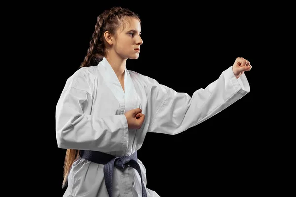 Close-up jonge vrouwelijke taekwondo atleet training geïsoleerd over donkere achtergrond. Begrip sport, onderwijs, vaardigheden — Stockfoto