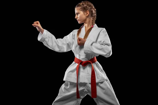 一个年轻的女孩，年轻的跆拳道运动员，在黑暗的背景下显得孤立无援。体育、教育、技能的概念 — 图库照片