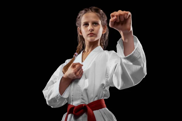 One young girl, teen, taekwondo athlete posing isolated over dark background. Concept of sport, education, skills — Stockfoto