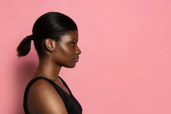 Joven hermosa mujer de piel oscura aislado en fondo de estudio rosa con espacio de copia para el anuncio. — Foto de Stock