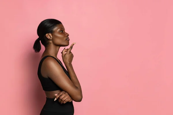 Vista de perfil de una joven hermosa mujer de piel oscura aislada sobre fondo de estudio rosa con espacio de copia para anuncios. — Foto de Stock