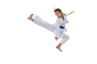 Genç kız, genç, tekvando atletinin dinamik portresi beyaz arka planda izole bir şekilde atlıyor. Spor, eğitim, beceri kavramı
