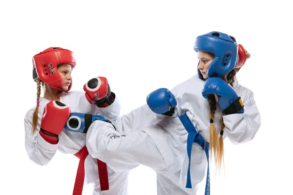 Tett på unge jenter, tenåringer, taekwondo-idrettsutøvere som øver sammen isolert over hvit bakgrunn. Begrepet idrett, utdanning, ferdigheter – stockfoto