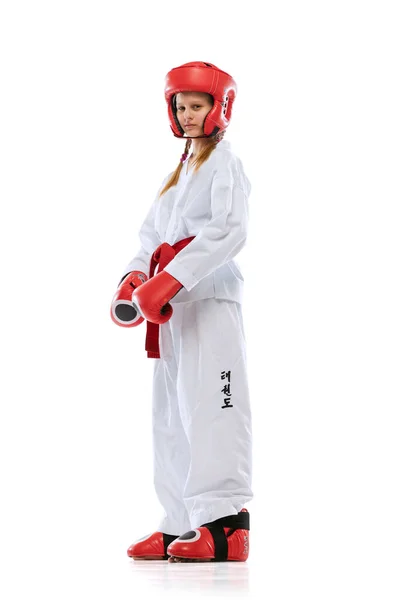 Full-length portrait of young girl, taekwondo athlete wearing dobok and sports defense uniform posing isolated on white background. — ストック写真