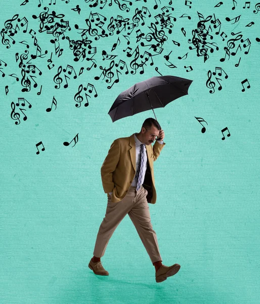 Contemporary art collage of serious man in suit walking with umbrella under falling music notes isolated over mint background Stock Picture