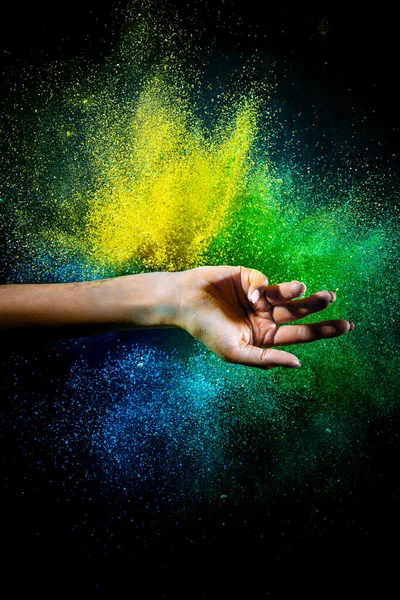 Female hand and explosion of colored, neoned powder on black studio background with copy space. Magazine cover, wallpaper design — Zdjęcie stockowe