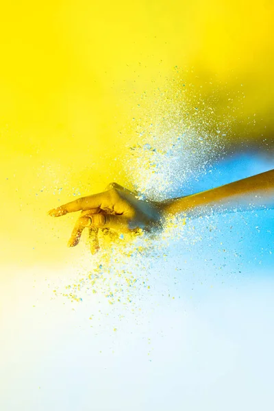 Yellow and white. Female hand and explosion of colored, neoned powder on bright studio background with copy space. Magazine cover, wallpaper design — 图库照片