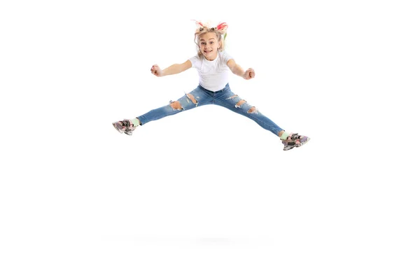 Эмоциональная красивая маленькая девочка, ребенок в повседневной одежде прыжки, весело изолированы на белом фоне студии. — стоковое фото