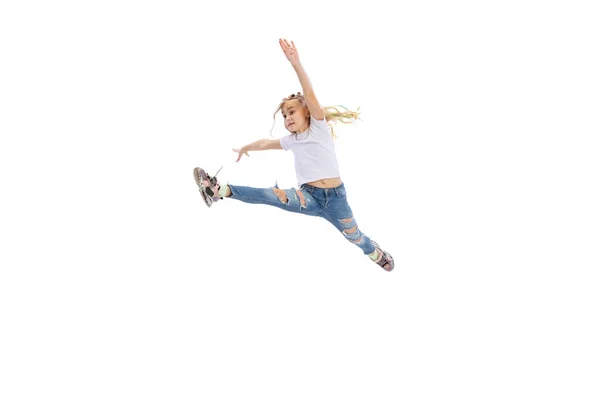 Dynamic portrait of little girl, kid in casual clothes jumping, having fun isolated on white studio background. — ストック写真