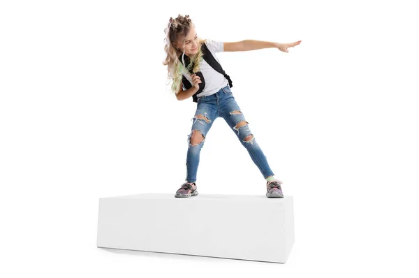 Full-length portrait of smiling girl in casual clothes standing on big box isolated on white studio background. Happy childhood concept. — Stock Photo, Image