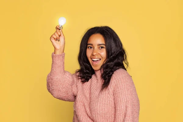 Retrato de media longitud de una chica joven de piel bastante oscura en suéter de punto cálido aislado sobre fondo amarillo. — Foto de Stock
