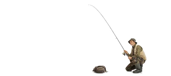 Portrait of young man, professional fisherman with fishing rod, spinning and equipment going to river isolated over white studio background — Fotografia de Stock