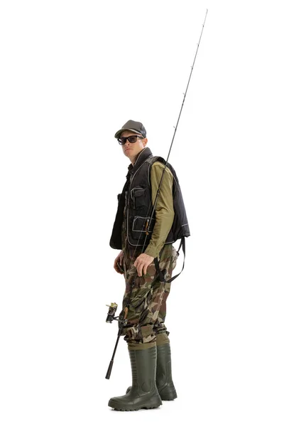 Portrait of young man, professional fisherman with fishing rod, spinning and equipment going to river isolated over white studio background — Stock Photo, Image