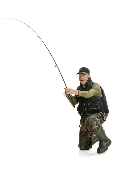 Portrait of young man, professional fisherman with fishing rod, spinning and equipment going to river isolated over white studio background — ストック写真