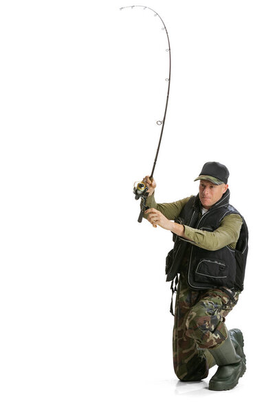 Portrait of young man, professional fisherman with fishing rod, spinning and equipment sitting isolated over white studio background