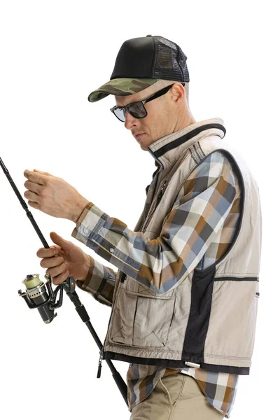 Portrait of young man, professional fisherman with fishing rod, spinning and equipment going to river isolated over white studio background — Fotografia de Stock