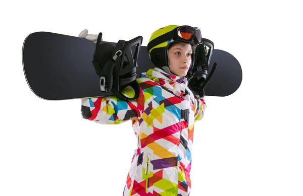 Close-up of young girl in bright sportswear, goggles and helmet standing with snowboard isolated on white studio background. Concept of winter sports — стоковое фото