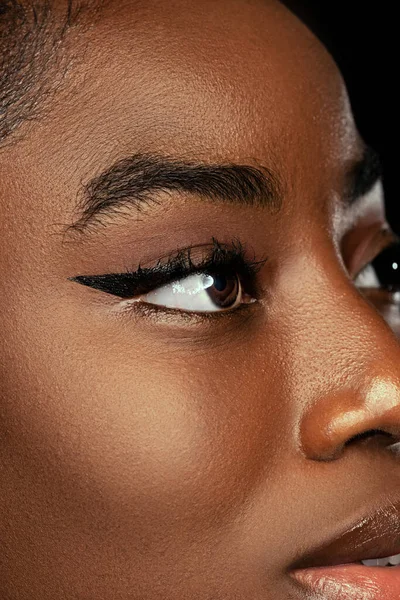 Close-up face of young african woman with well-kept skin isolated on dark studio background. Details. — Stockfoto