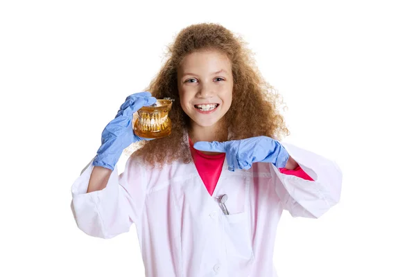 Portrait à mi-longueur d'une jolie petite fille mignonne, enfant à l'image d'un médecin dentiste portant un blouse blanche et des gants isolés sur fond de studio blanc — Photo