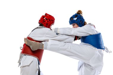 Dynamic portrait of two young women, taekwondo athletes training together isolated over white background. Concept of sport, skills