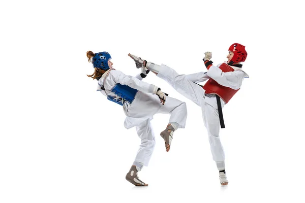 Portrait of two young women, taekwondo athletes practicing, fighting isolated over white background. Concept of sport, skills — Stock Photo, Image