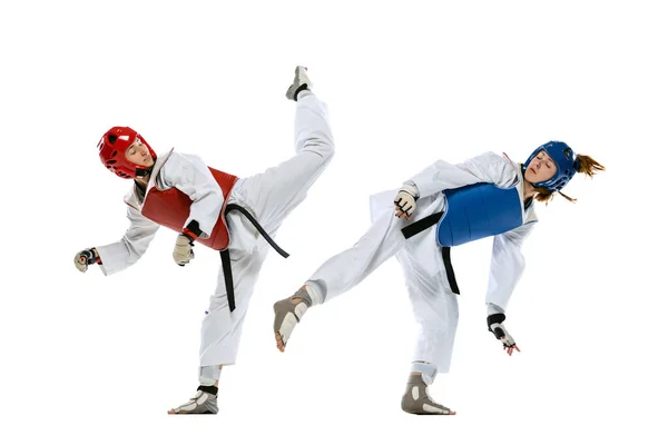 Dynamic portrait of two young women, taekwondo athletes training together isolated over white background. Concept of sport, skills — Stok fotoğraf