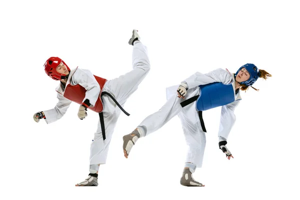 Dynamic portrait of two young women, taekwondo athletes training together isolated over white background. Concept of sport, skills — стоковое фото