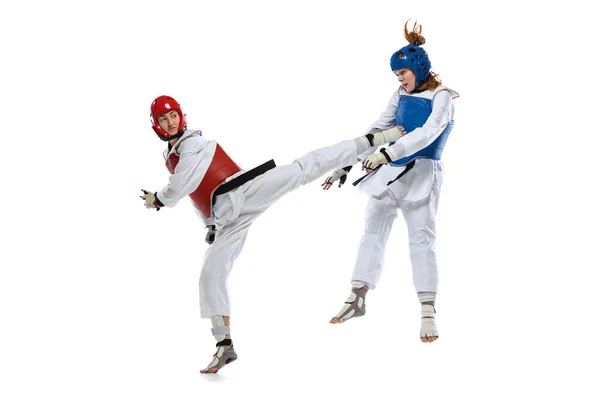 Retrato dinámico de dos mujeres jóvenes, practicantes de taekwondo entrenando juntas aisladas sobre fondo blanco. Concepto de deporte, habilidades — Foto de Stock