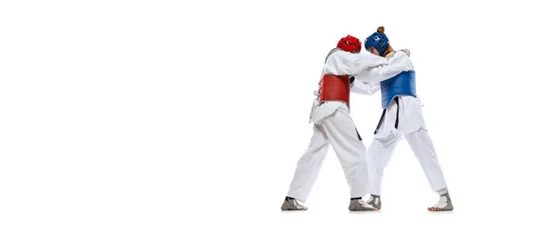 Portrait of two young women, taekwondo athletes practicing, fighting isolated over white background. Concept of sport, skills — Zdjęcie stockowe