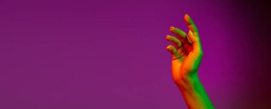 Aetentik insan eli kaldıran el ilanı, mor stüdyo arka planında, neon ışıkta izole edilmiş. İnsan ilişkileri, toplum, birliktelik kavramı